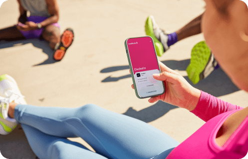 An employee checking the Wellova app on a phone at a gym.